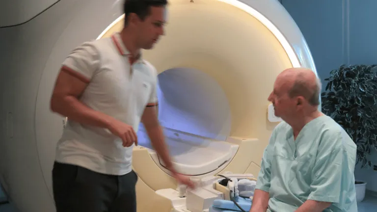 one man standing one elderly man sitting ready for an MRI exam
