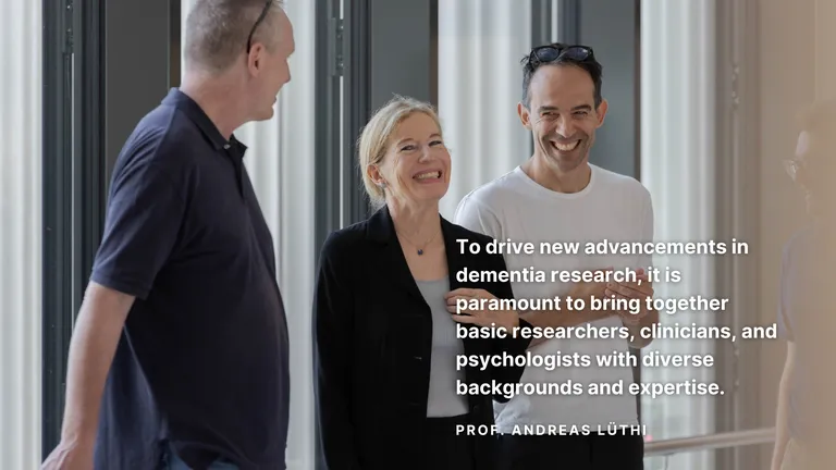 three people standing and laughing in hallway - quote by prof. Andreas Lüthi - To drive new advancements in dementia research it is paramount to bring together basic researchers, clinicians, and psychologists with diverse backgrounds and expertise.